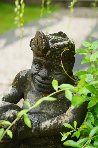 Elinde davul tutan ve çalıların arasında duran Balili bir adamın taş heykeli.