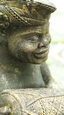 Bahçe süsü olarak davul taşıyan Balili bir adam şeklinde oyulmuş taş bir heykel.