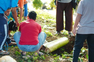 Bir grup adam Kurban Bayramı için bir keçi kesmek için bir çukur ve ağaç gövdesi hazırlıyor.