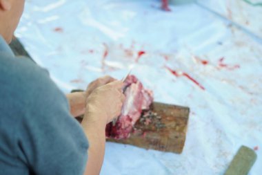 Kurban kesme töreninde et bıçağıyla tahta bir taban kullanan biri.