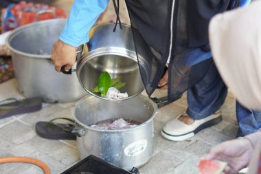 Bir insan tencereden tencereye güveç döker.