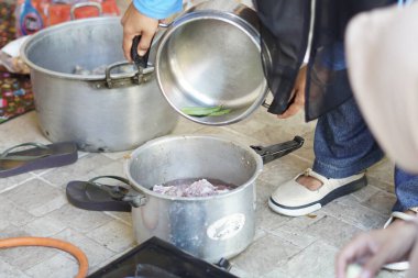 Bir insan tencereden tencereye güveç döker.