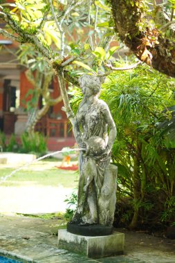 Yüzme havuzuna su püskürten bir sürahi tutan taş heykel.