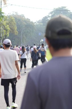 Bir grup insan sabah araba kullanmadan ana yolda yürüyor.