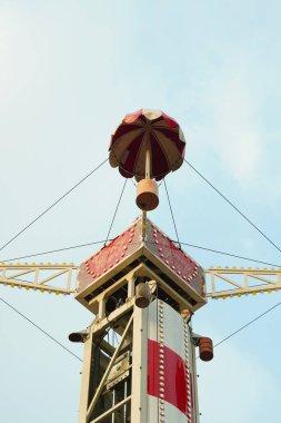 Mavi gökyüzü arkaplanı olan bir lunaparktaki kulenin tepesinde..