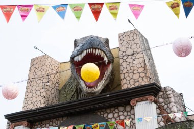 Ağzı açık büyük bir T-Rex heykeli ve ortasında da bir balon.