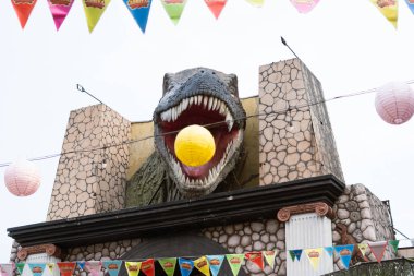 Ağzı açık büyük bir T-Rex heykeli ve ortasında da bir balon.