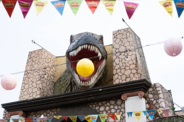 Ağzı açık büyük bir T-Rex heykeli ve ortasında da bir balon.