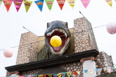 Ağzı açık büyük bir T-Rex heykeli ve ortasında da bir balon.