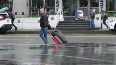 Kanada 'nın göbeğinde yağmurlu bir bahar var. Büyük anne ve büyük baba, şemsiyeli kadın ve erkekler, valizli insanlar, şehirde gezen yerel turistler. Merkezde yağmur var. Vancouver Kanada İngiliz Kolombiyası 05.04.2024