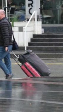 Kanada 'nın göbeğinde yağmurlu bir bahar var. Büyük anne ve büyük baba, şemsiyeli kadın ve erkekler, valizli insanlar, şehirde gezen yerel turistler. Merkezde yağmur var. Vancouver Kanada İngiliz Kolombiyası 05.04.2024