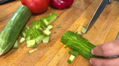 El, Salatalık Yüzüklerini Kesiyor. Tahta kesme tahtasının üzerinde taze salatalık kesen eller. Pişirmek için bıçakla sebze dilimlemek. Stok görüntüleri. - Evet. Yüksek kalite 4k görüntü