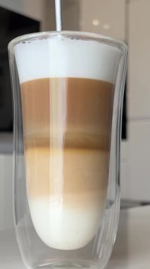Uzun saplı bir kaşıkla uzun bir bardak latte içinde el şekeri karıştırır. Bir kafede latte içerken yakın çekim. Yüksek kalite 4K görüntü. Yüksek kalite 4k görüntü