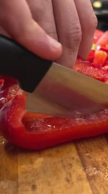  Yakından bakan adamlar kırmızı dolmalık biberi kesiyorlar. Sağlıklı yaşam tarzı yiyecekler. Sebze doğrayan adam. Gemide dilimlenmiş tatlı biber. Yemek pişirme, gastronomi ve aşçılık kavramı. - Evet. Yüksek kalite 4k görüntü