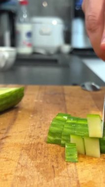 Aşçı domateslerden, salatalıklardan, yeşilliklerden ve karışımlardan oluşan bahar salatası keser. Salata için salatalık kesen kadın mutfak masasında salatalık kesiyor. Domates dalı ve soğan.