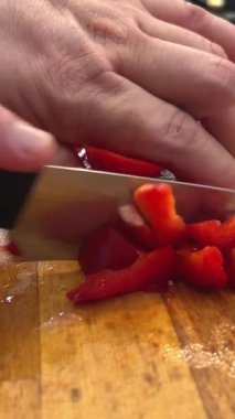 Şef kesme tahtasına kırmızı dolma biber koyar. Erkek eller sebze keser. Yüksek kalite 4k görüntü