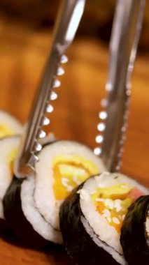 Sushi dürümleri yakın plan suşi için yemek çubuklarıyla alınır. Bir restoranda Japon mutfağı suşisi. Somon ve sebzeli suşi. Japon restoran menüsü. Yan görüş. Yüksek kalite 4k görüntü