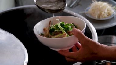 Vietnam 'da sokak yemeklerinde sahte çorba pişirmek sağlıksız koşullar turistlerin en sevdiği Asya çorbası. Erkek satıcı pirinç vermicelli çorbası hazırlıyor.