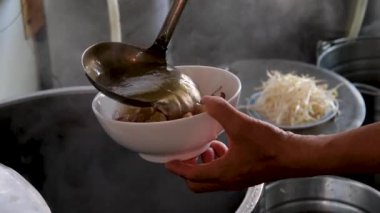Vietnam 'da sokak yemeklerinde sahte çorba pişirmek sağlıksız koşullar turistlerin en sevdiği Asya çorbası. Erkek satıcı pirinç vermicelli çorbası hazırlıyor.