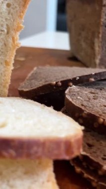 Şef somun ekmek dilimliyor. Buğday ve çavdar ekmeği dilimlenmiş. Yüksek kaliteli 4K görüntüler ekmekleri siyah kesiyor.