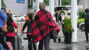 Kanada 'nın göbeğinde yağmurlu bir bahar var. Büyük anne ve büyük baba, şemsiyeli kadın ve erkekler, valizli insanlar, şehirde gezen yerel turistler. Merkezde yağmur var. Vancouver Kanada İngiliz Kolombiyası 05.04.2024