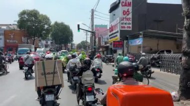 Şehir merkezindeki büyük bir şehirde trafik vardı. İnsanlar motosiklet kullanıyordu. Yol kuralları yoktu, maskeler takıyorlardı.. 