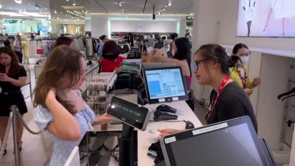 在越南的一家商店里 一个欧洲女孩在收银台选购衣服 亚洲和跨国妇女 男人选购衣服 出纳员开具收据 越南胡志明市05 2024 — 图库视频影像