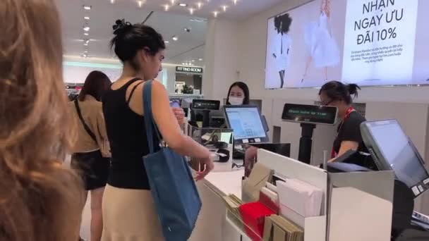 在越南的一家商店里 一个欧洲女孩在收银台选购衣服 亚洲和跨国妇女 男人选购衣服 出纳员开具收据 越南胡志明市05 2024 — 图库视频影像