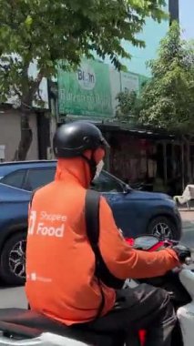 Ho Chi Minh City 'den yiyecek teslimatı, markalı turuncu ceketli bir motosikletçi teslimat yapıyor. Şehirdeki gerçek hayat. Vietnam Ho Chi Minh Şehri 05.11.2024 