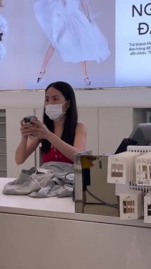 Vietnam 'da bir mağaza, Avrupalı bir kız kasada kıyafet seçiyor, Asyalı ve çok uluslu kadınlar, erkekler kıyafet alıyor, kasiyer makbuz veriyor, Vietnam Ho Chi Minh City 05.11.2024