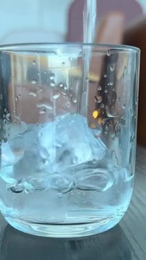 Saf su, açık gri arka planda cama yakın çekim olarak döküldü. Süper yavaş çekim. Susuzluğu giderme konsepti. Temiz içme suyu dolgu bardağını kapatın. Yüksek kalite 4k görüntü