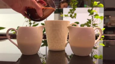 V60 'ta bir fincan kahve yapma süreci. İş yerindeki barista koyu kahveyi kağıt filtreye çevirir. Hüner sütlü kahveyi cam beyaz bir kasede karıştırır.