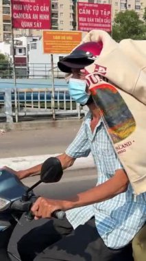 İnsanlar ceketleriyle kendilerini güneşten korumak için motosiklet sürerken gözleri kapalı bir şekilde maske takıyor ve Vietnamlı kaskı takıyorlardı. İnsanlar evlerine gidiyor..