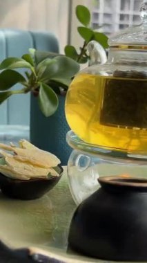 Taze çiğ yeşil çay yaprağı tomurcuğu limon portakal, şeffaf cam çay fincanı çay fincanı, beyaz arka plan manzaralı pan zoom üzerinde döner. Yüksek kalite 4k görüntü