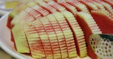 Popüler yaz içeceği. Eller tabaktan kırmızı karpuz dilimlerini alıyor ve temizliyor. Kamera kaydı. Karpuz dilimleri. Karpuz dilimleri. Bıçakla kolay yenen porsiyonlar.