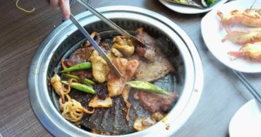 Vietnam, restorandaki bir masada kızartma tavasında et kızartıyor. Akşam yemeği için bir kafede baharatlı et hazırlanıyor.