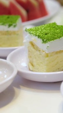 Açık büfedeki porsiyonlu pandispanya üzerine yeşil dondurulmuş şam fıstığı meyvesi serpiştirilmiş. Yüksek kaliteli FullHD görüntüler