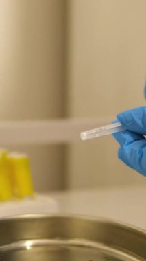 Mavi eldiven, laboratuarda durup test tüpünü tutabilmek için vakum tüpü yerleştirdi. Mikro küp. Vakum kan toplama tüpü.