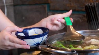Yanan kız sıcak çorbayla elini yakar kaynayan suyu dökerek büyük bir deriye sıçratır ve acı verici bir şekilde elini çeker. Yüksek kalite 4k görüntü