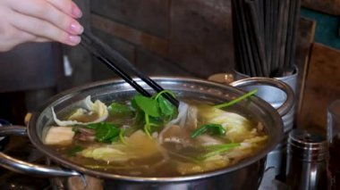 Yakın plan kızartma tavasında et suyu pilavı pilav vermicelli ve sebzeli kız Vietnam 'ı pişirmek için açık büfede yemeğini karıştırıyor. Vietnam çorbası pişir..