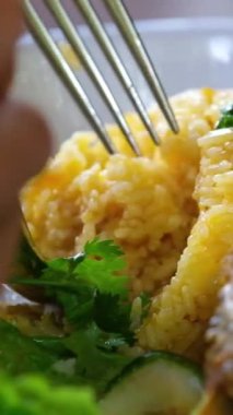 Tofu, yumurta, vermicelli ve orek tempe ile servis edilen Endonezya sarı pirinci. El çatalla yemek topluyor.