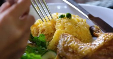 Tofu, yumurta, vermicelli ve orek tempe ile servis edilen Endonezya sarı pirinci. El çatalla yemek topluyor.