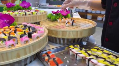 Şef bir restoranda ahşap tepsiye suşi koyar. Suşi büfesi