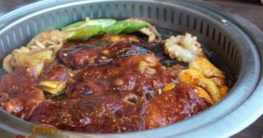 Adam büyük bir tavada et pişiriyor. Kırmızı ve beyaz kızartma tavasını et ile karıştırmak için spatula kullanıyor. Masada et kızart.