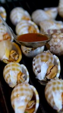 Salyangoz deniz mahsulü insan ızgarada deniz salyangozu pişiriyor. Yüksek kaliteli FullHD görüntüler