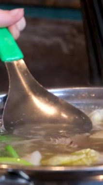 Yakın plan kızartma tavasında et suyu pilavı pilav vermicelli ve sebzeli kız Vietnam 'ı pişirmek için açık büfede yemeğini karıştırıyor. Vietnam çorbası pişir..