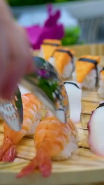 Suşi plastik bir kutuda yuvarlanır ve siyah arka planda yakın plan çekilir. Lezzetli Japon dürümleriyle dolu hazır suşi kutusu teslimat konteynerinde. Yemek teslimatı, paket yemek.. 