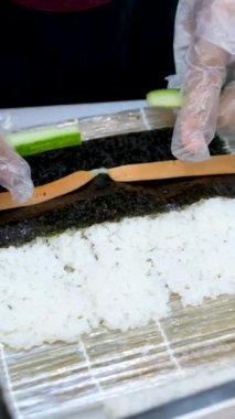 Suşi plastik bir kutuda yuvarlanır ve siyah arka planda yakın plan çekilir. Lezzetli Japon dürümleriyle dolu hazır suşi kutusu teslimat konteynerinde. Yemek teslimatı, paket yemek.. 
