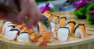 Suşi plastik bir kutuda yuvarlanır ve siyah arka planda yakın plan çekilir. Lezzetli Japon dürümleriyle dolu hazır suşi kutusu teslimat konteynerinde. Yemek teslimatı, paket yemek.. 