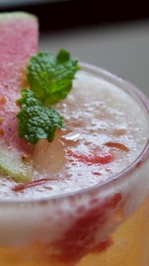 Kırmızı guava suyu ağacın arka planında bulanık bir bardağa dökülüyor. Meyve suyu hazırlanıyor. Ağır çekim. Yüksek kalite 4k görüntü